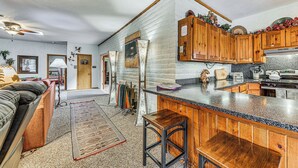 A kitchen with wooden cabinets, a granite countertop, and a bar stool. - Spacious Alto House on 8 Private Acres w/ Hot Tub! (Alto)