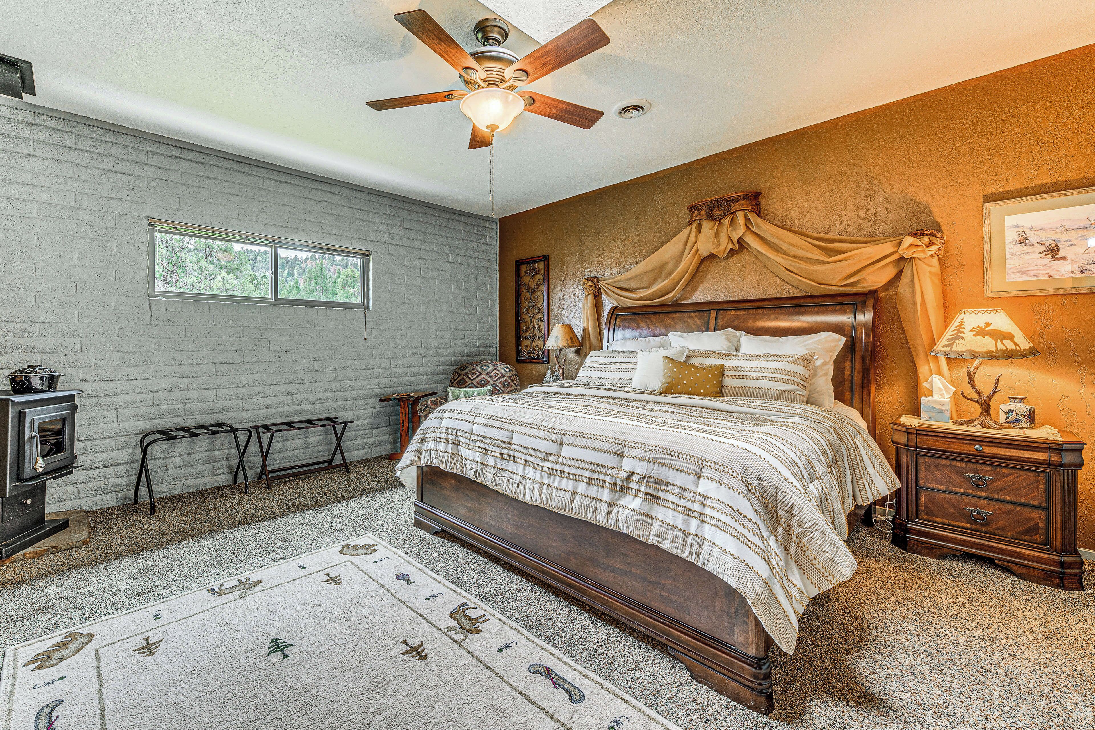 A bedroom with a wooden bed, a ceiling fan, a window, and a nightstand with a lamp.