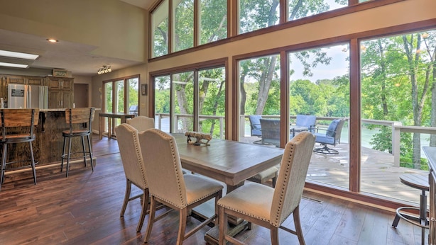 A spacious kitchen with large windows, a dining area with chairs, and a view of the outdoors. - Lakefront Home w/ Fishing Dock & Fire Table! (Hollister)