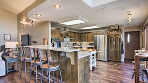 A spacious kitchen with a large island, wooden cabinets, and modern appliances. - Lakefront Home w/ Fishing Dock & Fire Table! (Hollister)