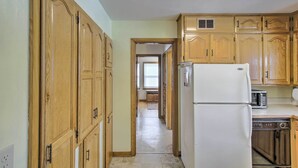 A kitchen with wooden cabinets, a white refrigerator, a dishwasher, and a microwave. - Cozy Oshkosh Home, 4 Blocks to Lake Winnebago (Oshkosh)