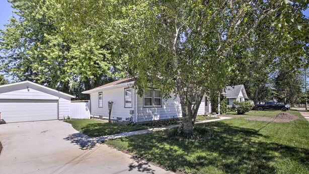 A single-story house with a garage, a small front yard, and a tree providing shade. - Cozy Oshkosh Home, 4 Blocks to Lake Winnebago (Oshkosh)