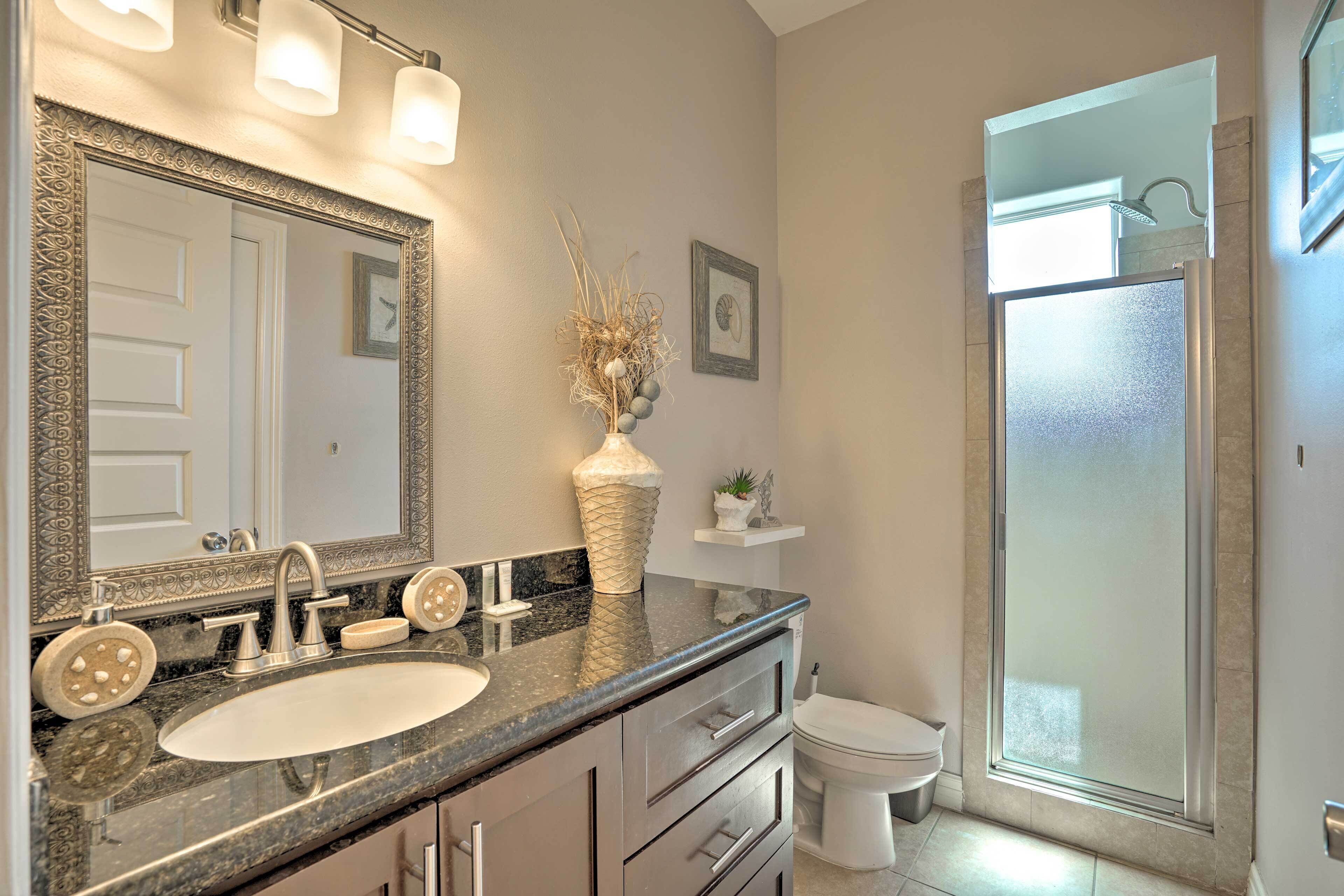A bathroom with a large mirror, a sink, a toilet, and a shower.