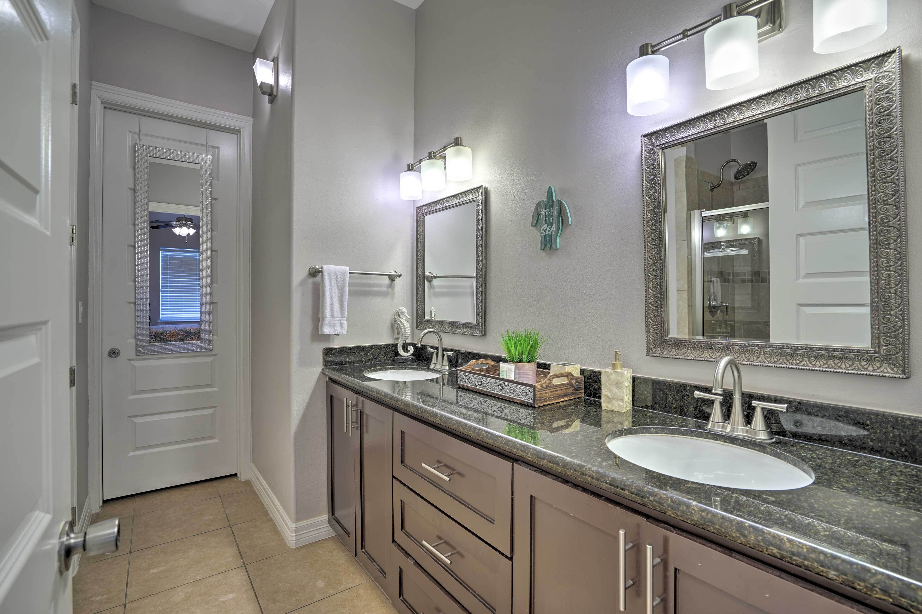Une salle de bain avec deux lavabos, un grand miroir et un meuble-lavabo avec des tiroirs.