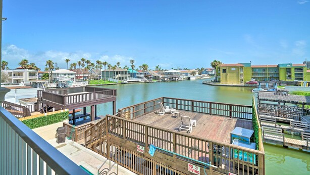 A waterfront view with a wooden deck, lounge chairs, and a 'No Diving' sign. - Updated Fiesta Isles Condo w/ Bay Views & Pool! (South Padre Island)