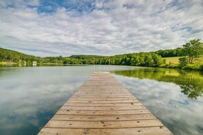 Een houten steiger die zich uitstrekt over kalm water, omringd door weelderige begroeiing en heuvels.