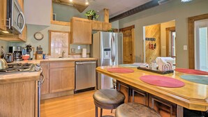 A modern kitchen with wooden cabinets, stainless steel appliances, and a central island with stools. - Historic Manitou Springs Victorian: Walk Downtown! (Manitou Springs)