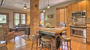 A kitchen with a central island, bar stools, wooden cabinets, a microwave, and an oven. - Historic Manitou Springs Victorian: Walk Downtown! (Manitou Springs)