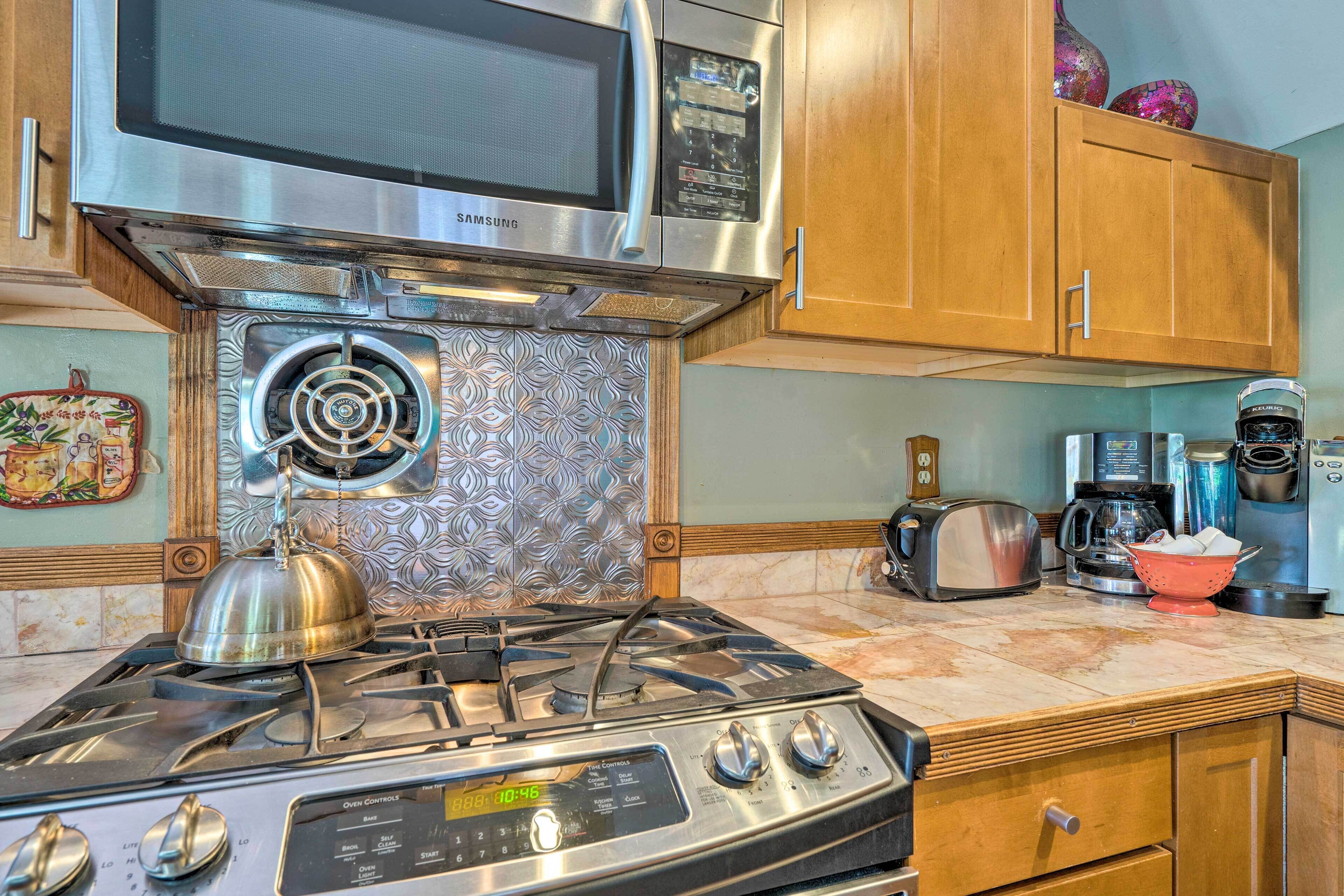 A kitchen with a stainless steel stove, a microwave, and wooden cabinets.