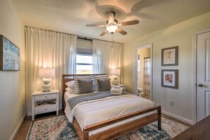 A bedroom with a bed, nightstands, a ceiling fan, and a window with curtains. - Modern Oasis w/ Grill and Deck - Walk to Beach! (Freeport)