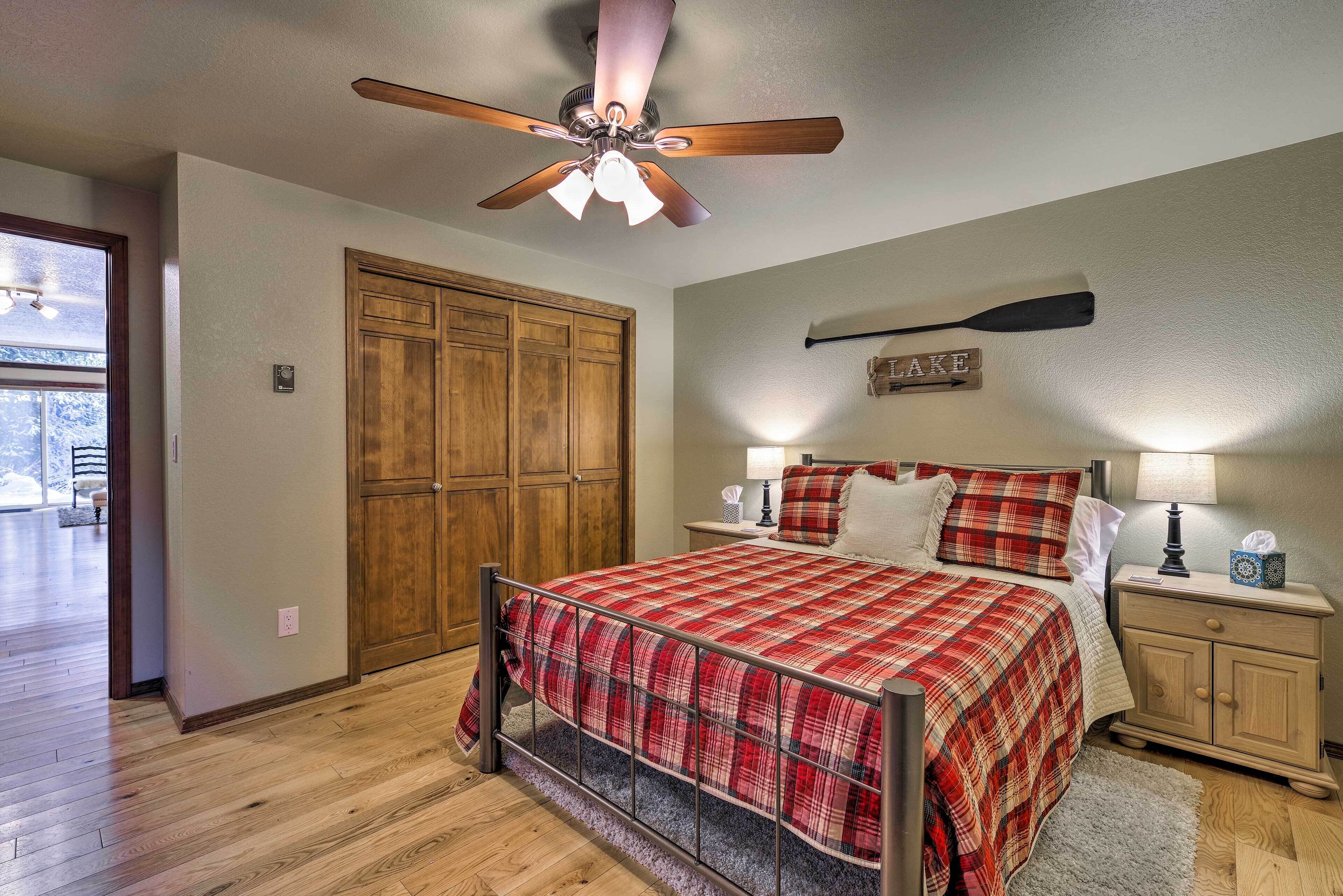 Une chambre à coucher comprenant un lit, une armoire en bois, un ventilateur de plafond et une table de chevet avec une lampe.