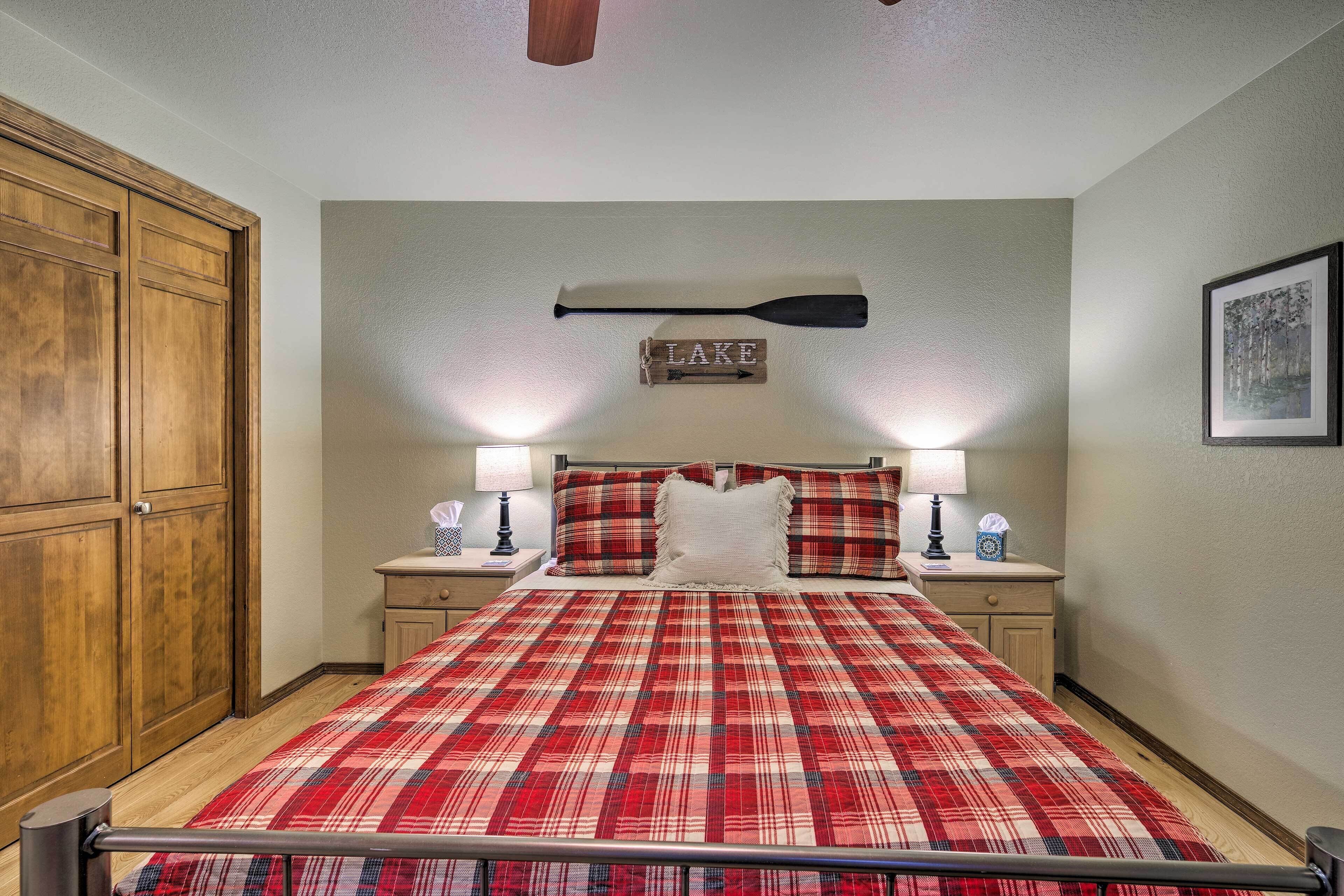 A bedroom with a plaid bedspread, wooden wardrobe, and a wall-mounted sign that reads "LAKE".