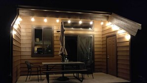 Une petite terrasse extérieure agréable, avec une table et des chaises, un auvent et une porte donnant sur l’intérieur.