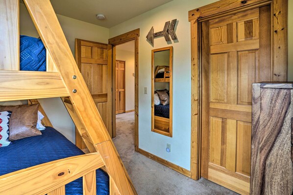 Une chambre avec un lit superposé, des portes en bois et un miroir au mur.