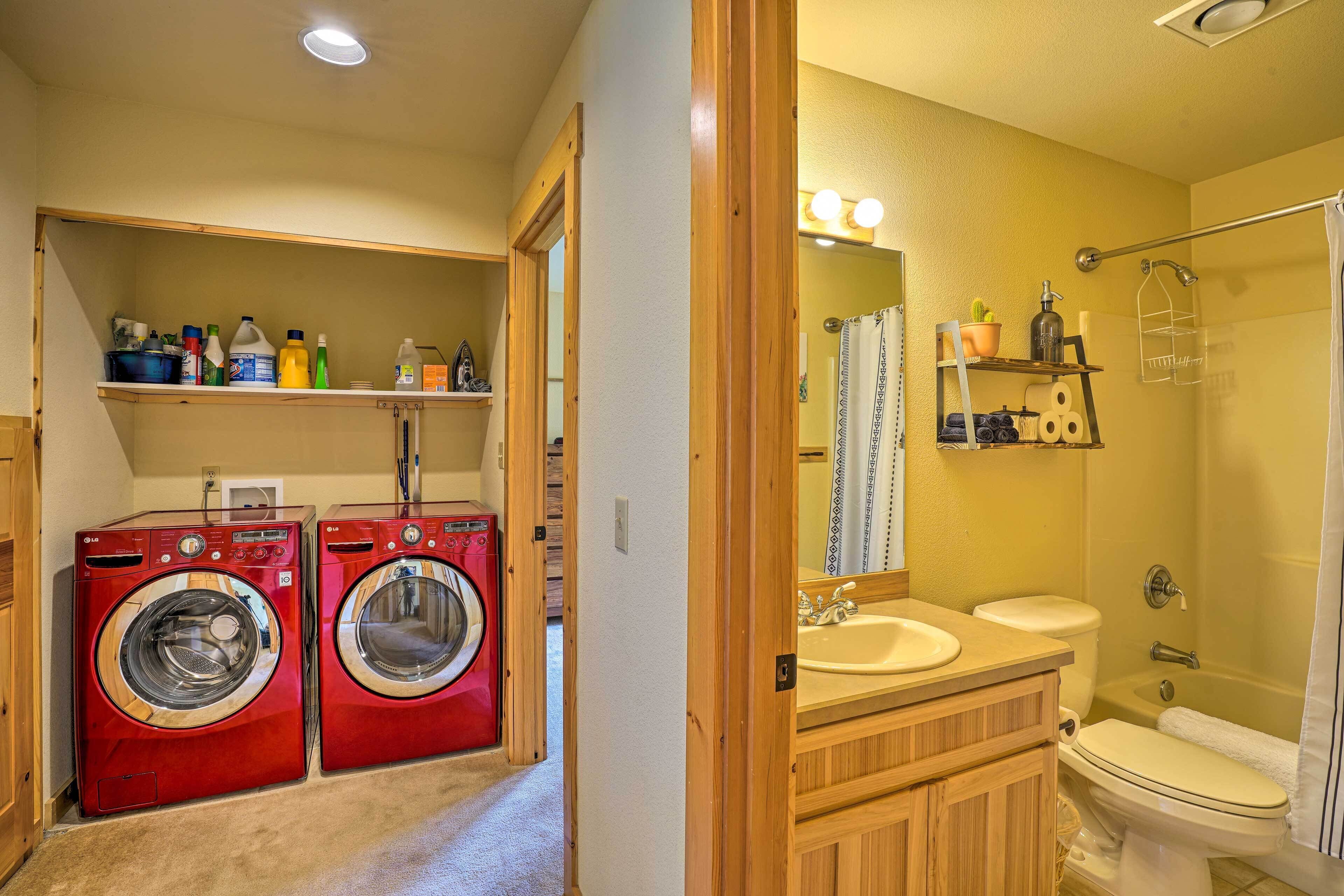 A laundry area with two red washing machines, a wooden vanity with a sink, and a shower with a glass door.