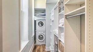 A narrow laundry room with stacked laundry baskets, a washing machine, and a dryer. - Contemporary Cincinnati Condo - Pets Allowed! (Cincinnati)