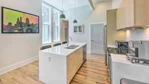 A modern kitchen with a central island, wooden cabinets, and built-in appliances. - Contemporary Cincinnati Condo - Pets Allowed! (Cincinnati)