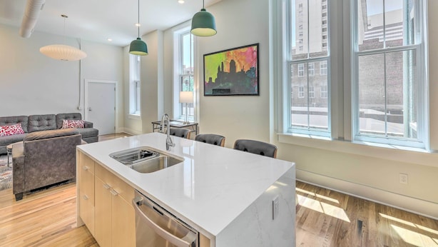 A modern kitchen with a white countertop, stainless steel sink, and overhead pendant lights. - Contemporary Cincinnati Condo - Pets Allowed! (Cincinnati)