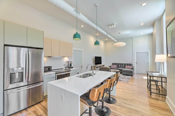 A modern kitchen with a central island, stainless steel appliances, and bar stools. - Contemporary Cincinnati Condo - Pets Allowed! (Cincinnati)