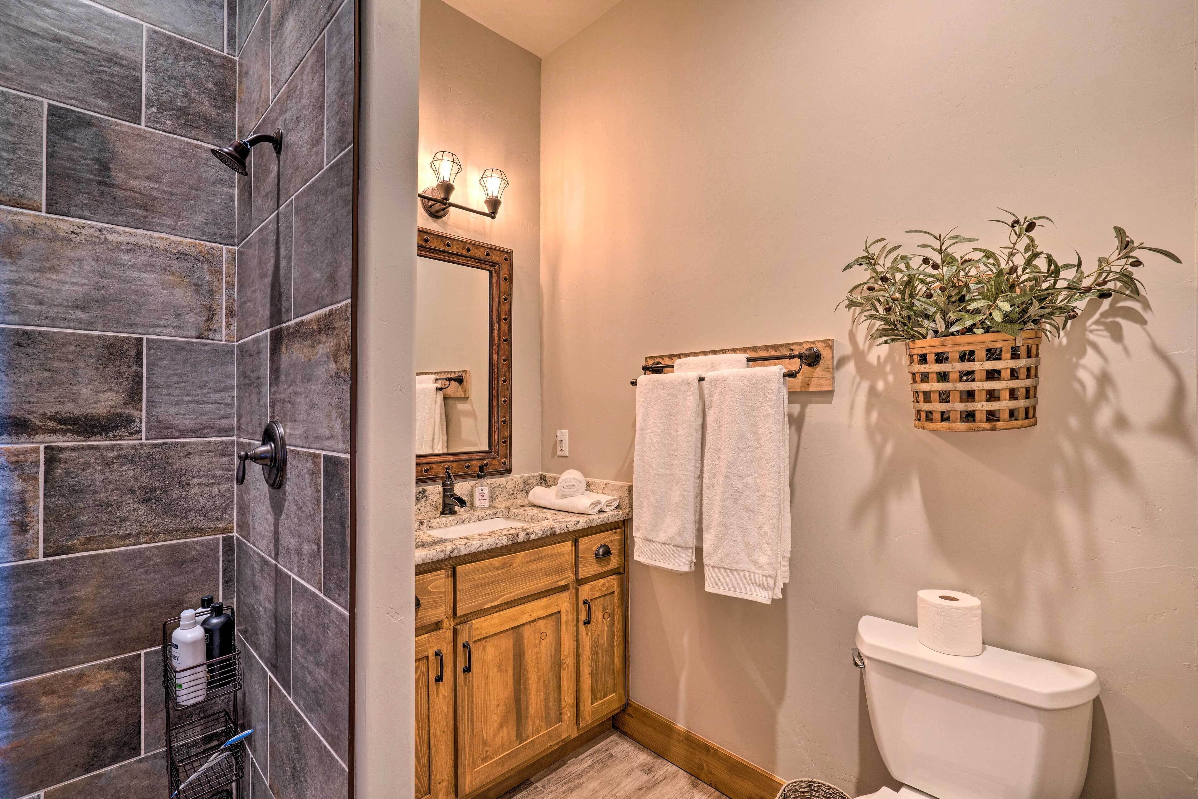 A bathroom with a shower, wooden cabinets, a sink, a toilet, and a hanging plant.