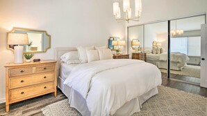 Ein Schlafzimmer mit einem großen Bett, einem Schminktisch, Nachttischlampen und einem Spiegel.