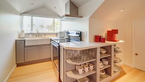 A modern kitchen with a central island, built-in oven, and a window with blinds. - Victorian Carpinteria Apartment < 1 Mi to Beach! (Carpinteria)