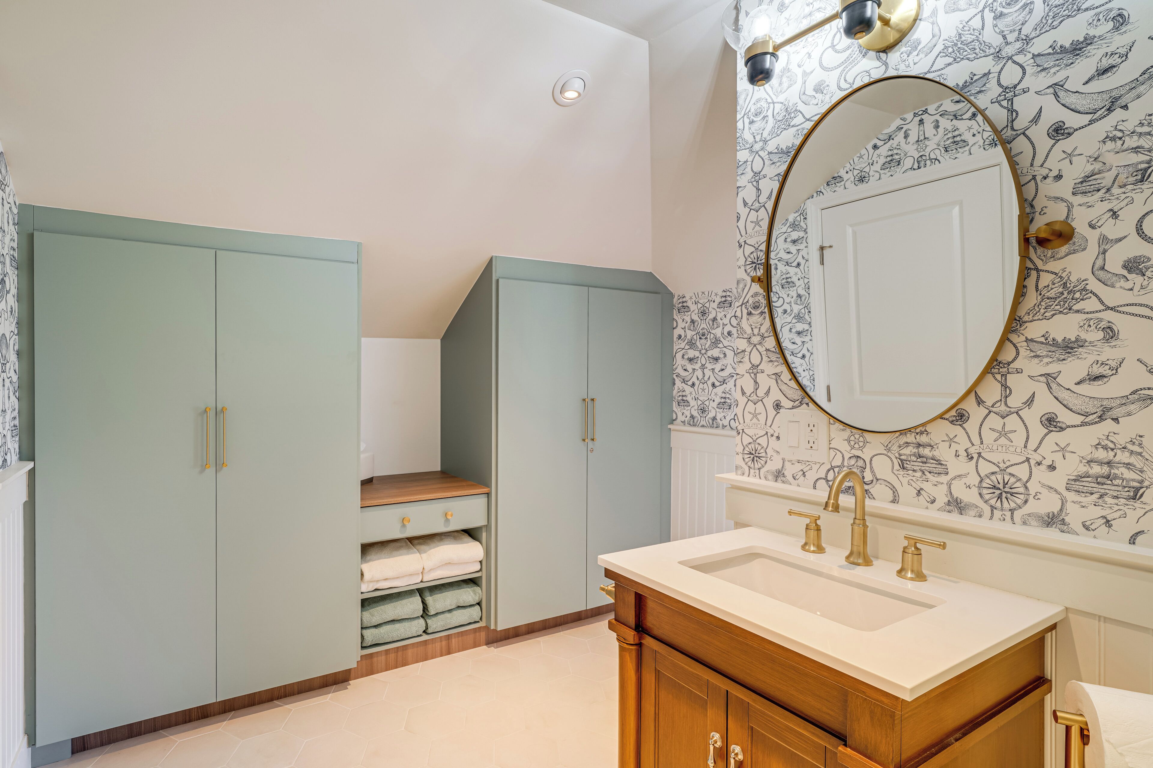 A bathroom with a large mirror, a sink, and two cabinets.