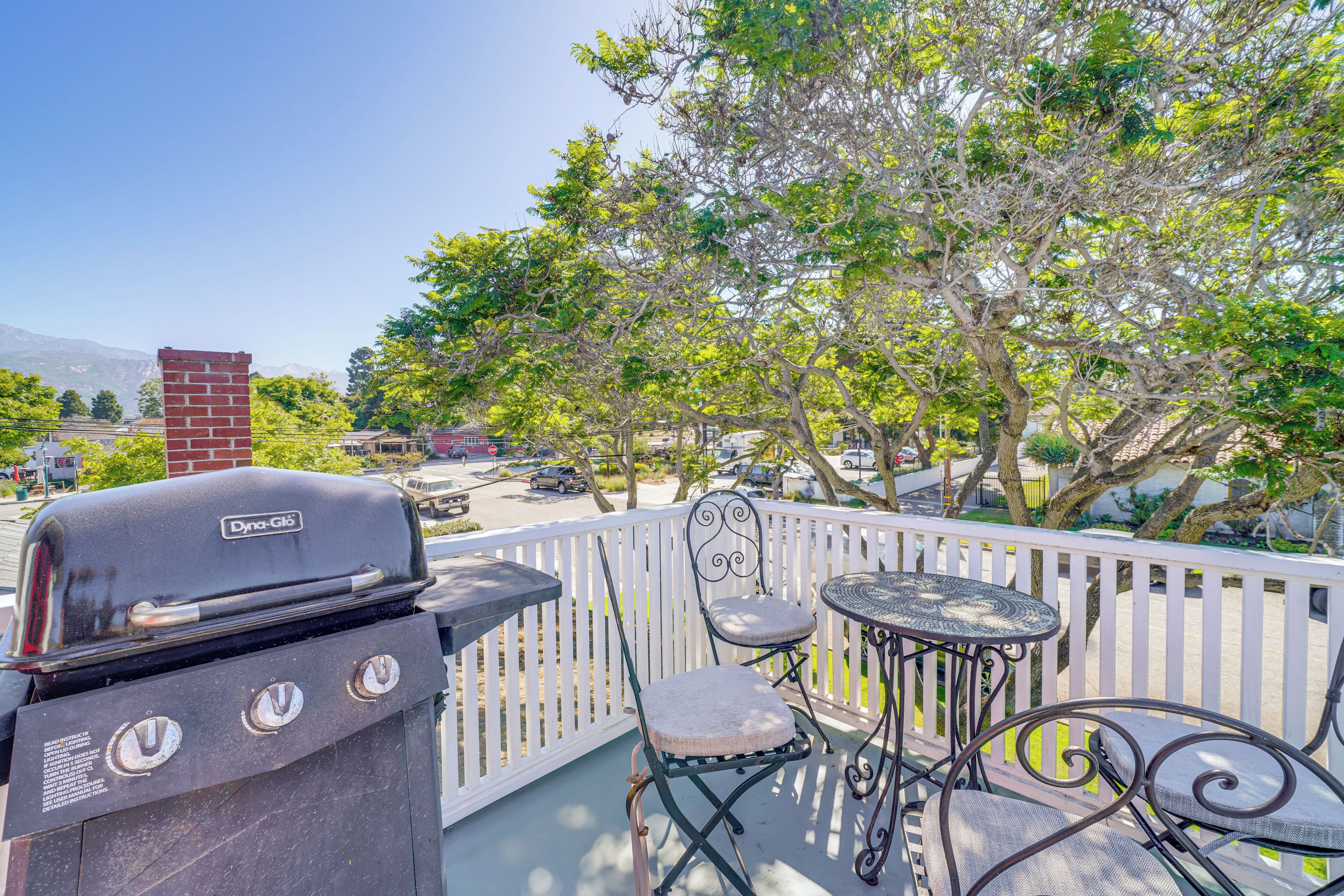 A balcony with a grill, a chair, and a small table.