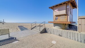 A lifeguard tower with a signboard, a wooden bench, and a concrete staircase leading to the beach. - Victorian Carpinteria Apartment < 1 Mi to Beach! (Carpinteria)