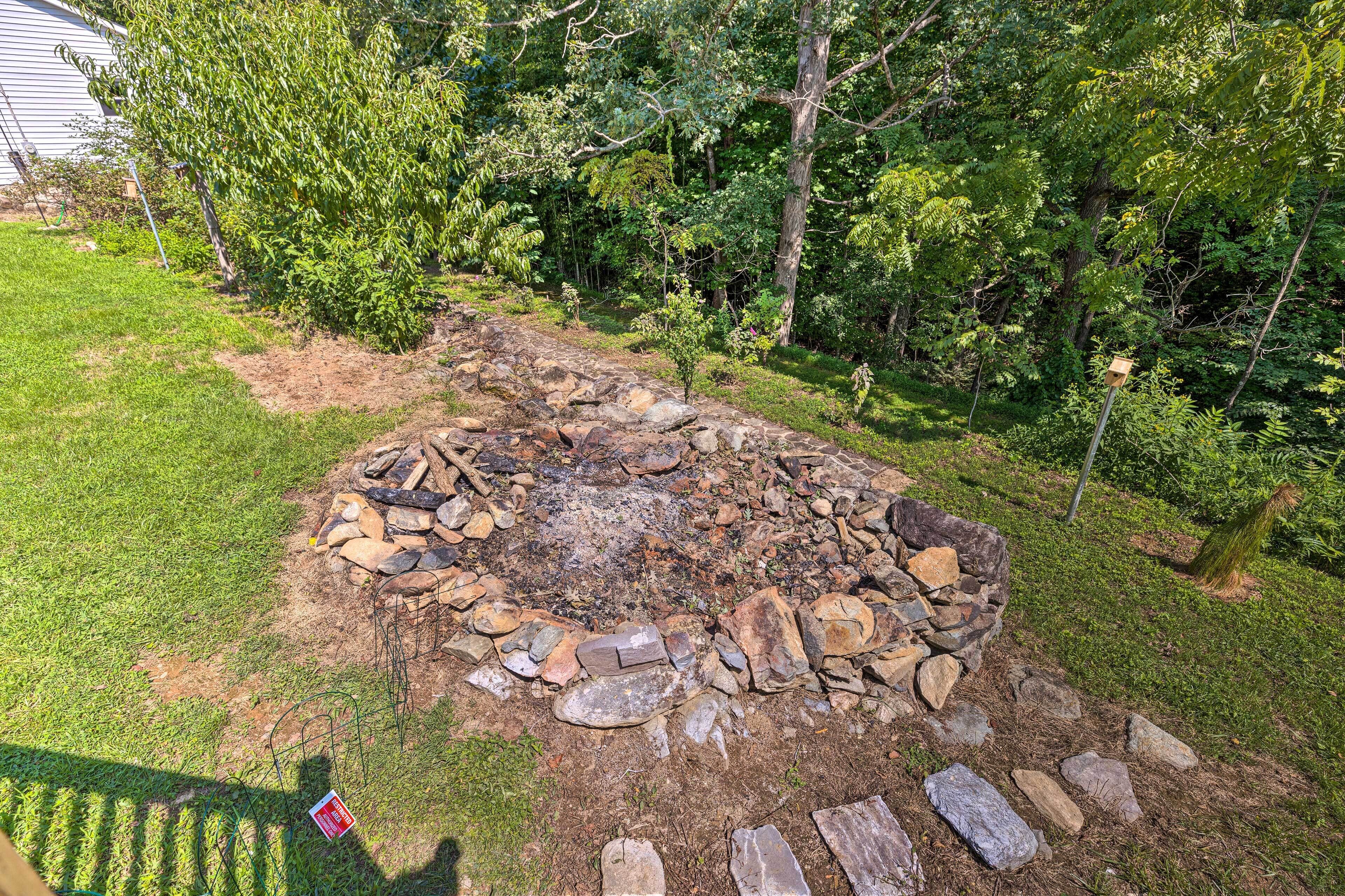 Un espace jardin aménagé avec un foyer en pierre, entouré de rochers et de verdure.