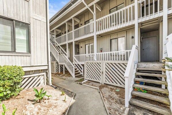 A multi-story building with a central staircase, a small garden area, and a door at the bottom of the stairs.