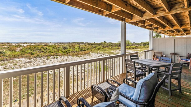 A wooden deck with outdoor furniture, a railing, and a view of the beach. - Oceanfront St Helena Island Condo w/ Beach Access! (Harbor Island)