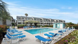 A pool area with lounge chairs, a swimming pool, and a multi-story building with balconies. - Oceanfront St Helena Island Condo w/ Beach Access! (Harbor Island)