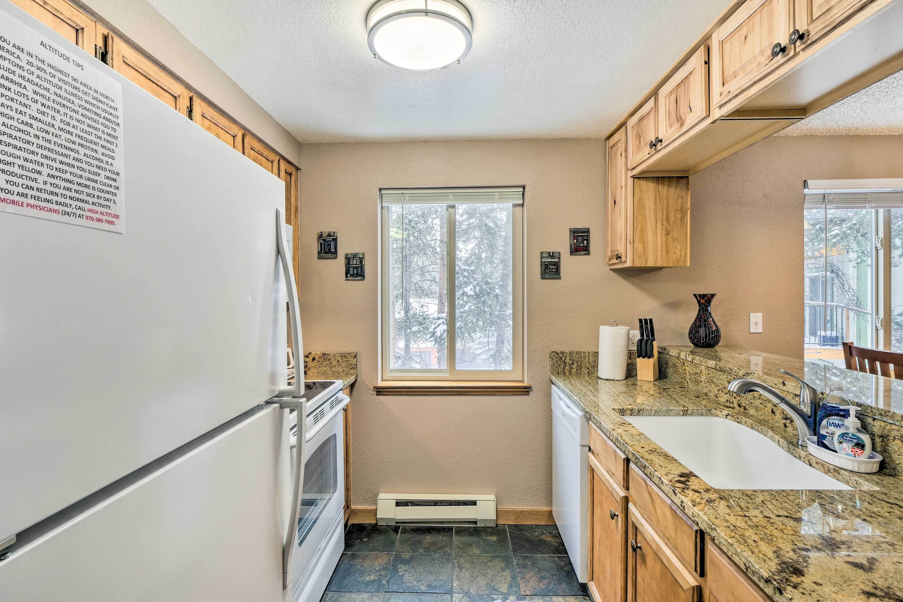 Una cocina con refrigerador, estufa, lavaplatos y ventana.