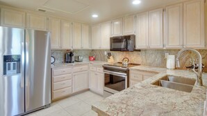 A modern kitchen with stainless steel appliances, marble countertops, and light-colored cabinetry. - 112117: Spacious 3 BR La Quinta Condo on PGA West! (La Quinta)