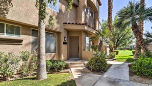 A stucco building with a front door, a small porch, and a well-maintained lawn with palm trees. - 112117: Spacious 3 BR La Quinta Condo on PGA West! (La Quinta)