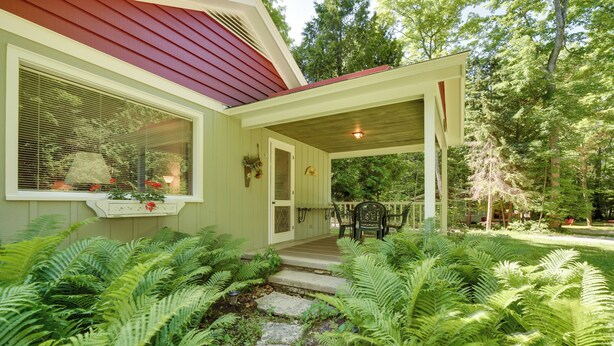 A house with a porch, steps leading to the entrance, and a garden with ferns. - 'cherry Cottage' - Walk to Peninsula State Park! (Ephraim)