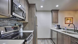 A modern kitchen with stainless steel appliances, a granite countertop, and wooden cabinets. - Walk to Main Street: Frisco Townhome w/ Decks (Frisco)