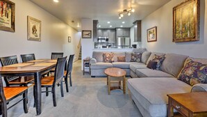 A modern living room with a dining area, grey sofa, wooden dining table, and chairs. - Walk to Main Street: Frisco Townhome w/ Decks (Frisco)