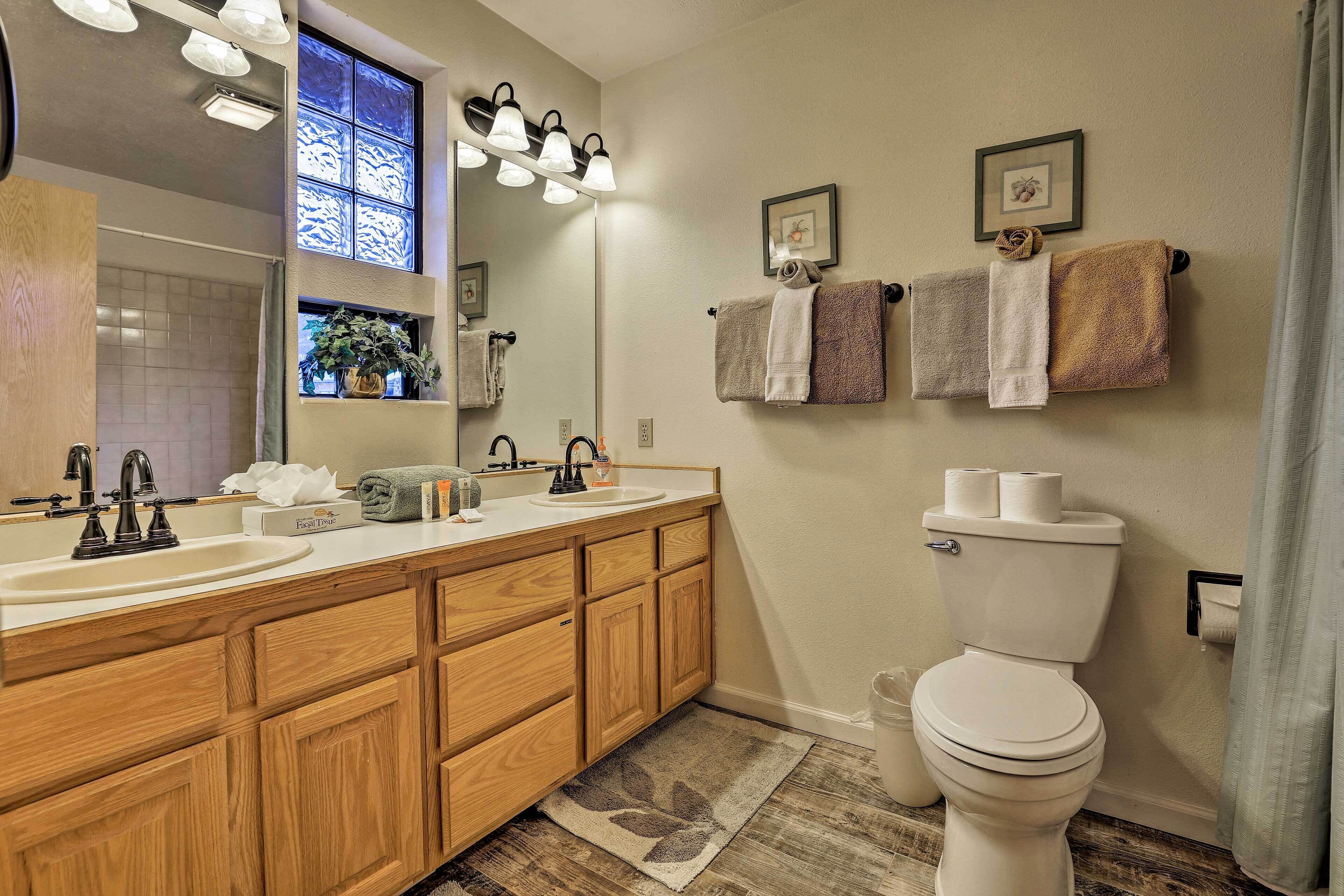 Une salle de bain avec des meubles en bois, un lavabo blanc, des toilettes et un miroir avec éclairage intégré.