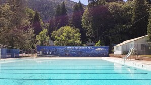A clear swimming pool with a mural in the background, surrounded by trees and a mountainous landscape. - Dunsmuir Apartment ~ 17 Mi to Mt Shasta Ski Park! (Dunsmuir)