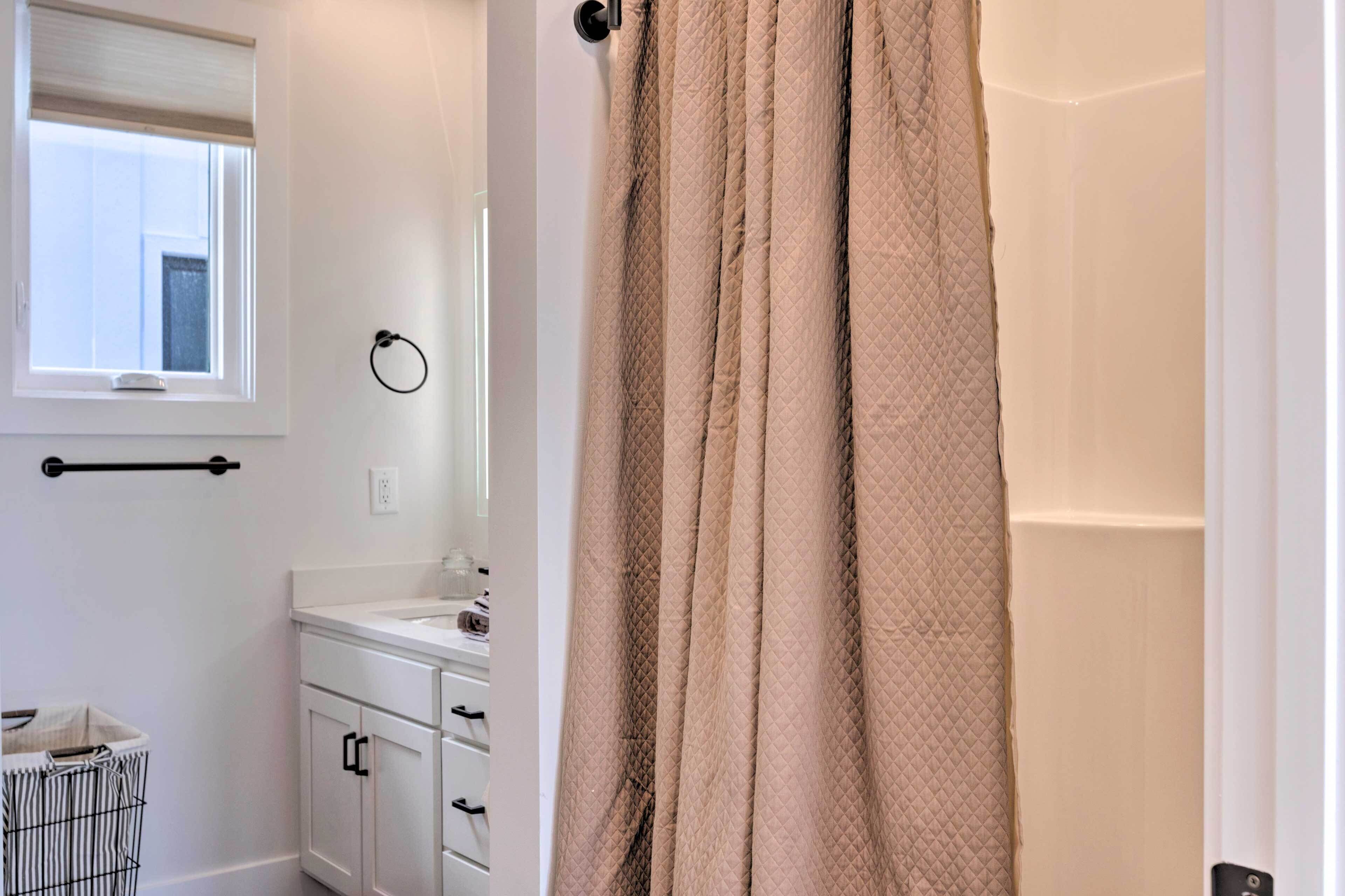 A bathroom with a white sink, a mirror, a towel rack, and a beige shower curtain.