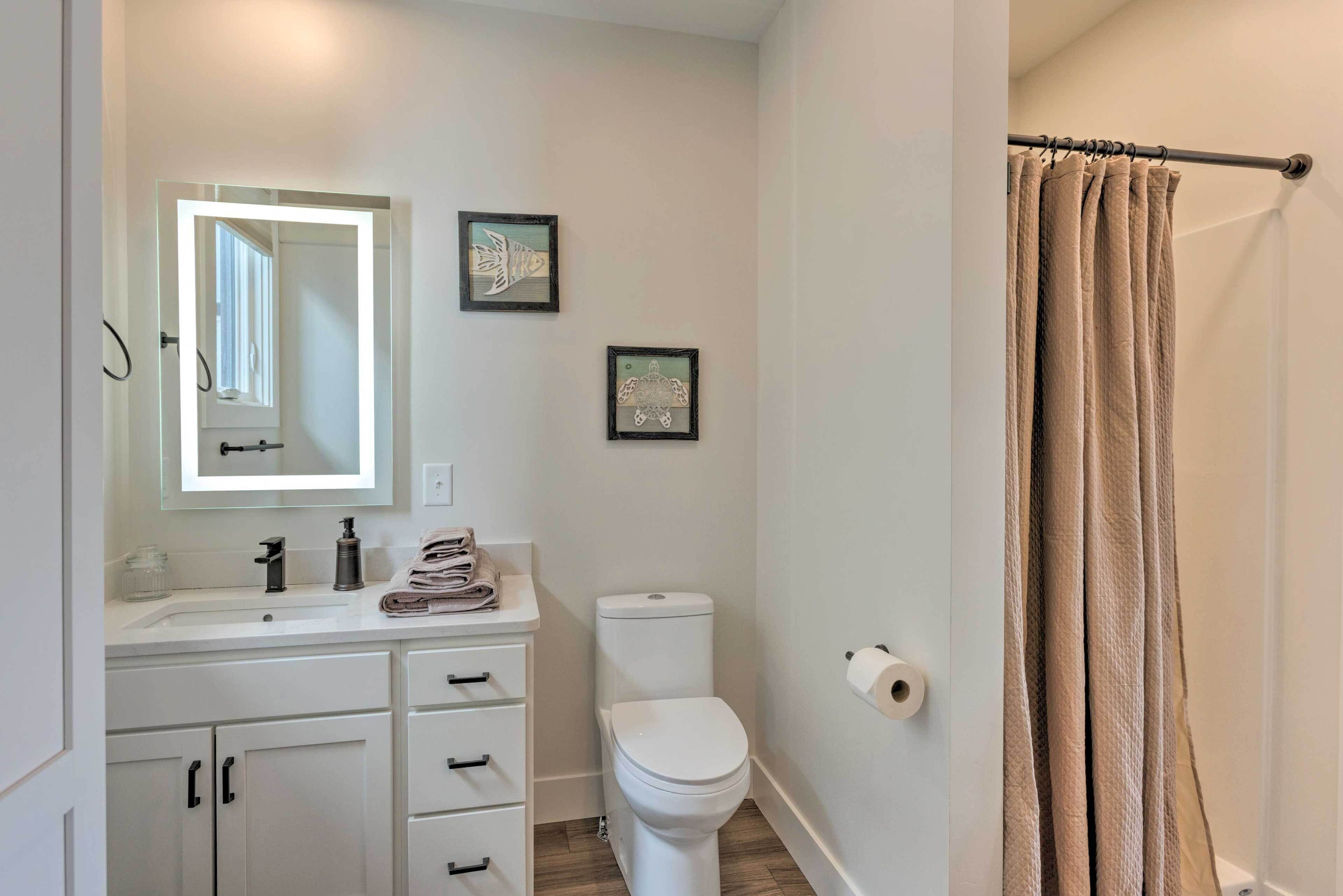 A bathroom with a white sink, mirror, toilet, and beige curtains.