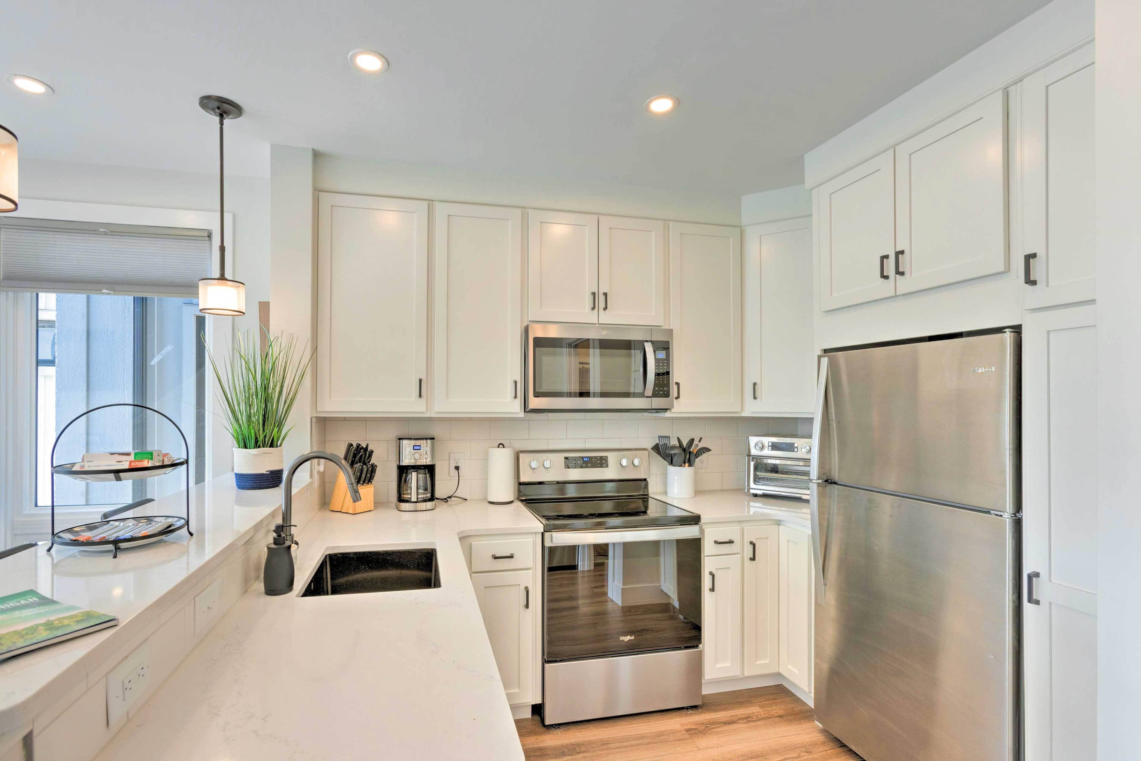 A modern kitchen with white cabinets, stainless steel appliances, and a wooden countertop.