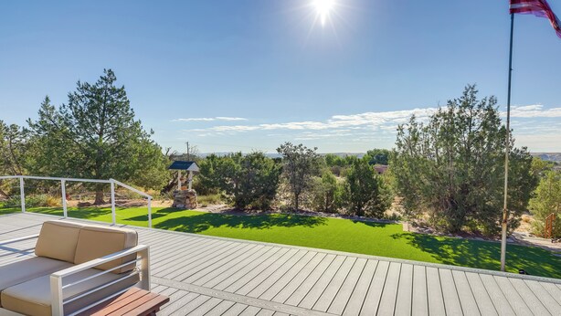 A wooden deck with a sofa and a bench, overlooking a well-maintained lawn and trees. - Home w/ Views & Fire Pit, 10 Mi to Aztec Ruins! (Farmington)