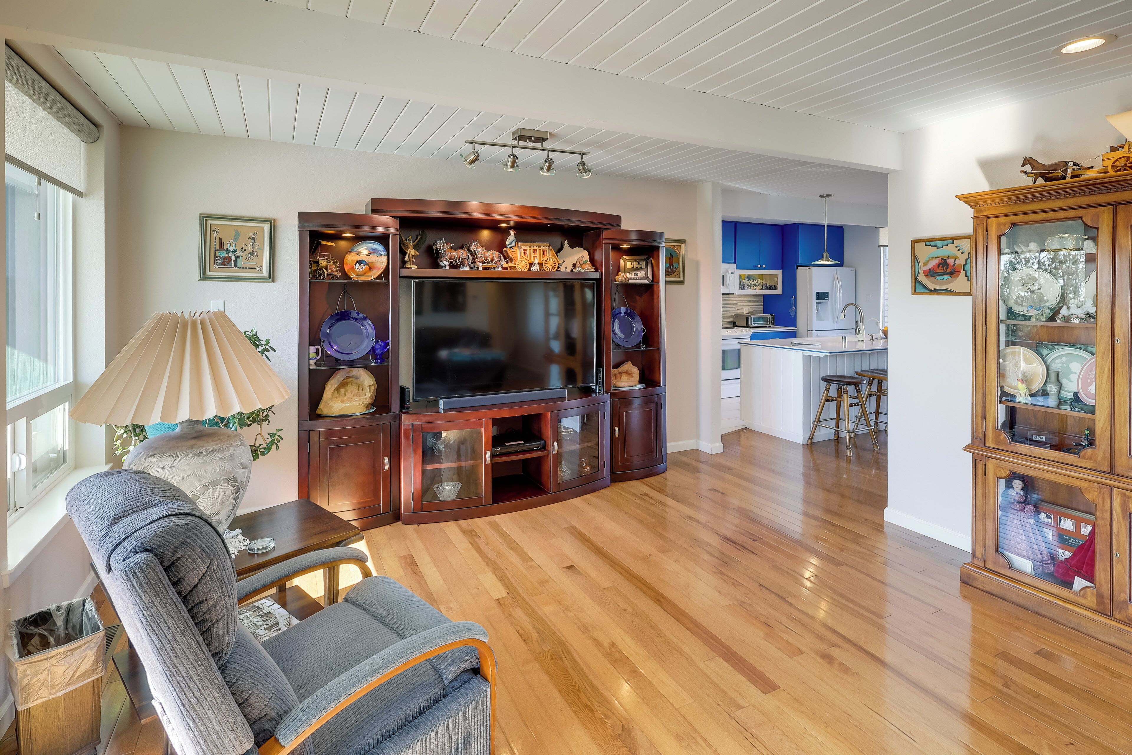 Una sala de estar con un mueble de madera para entretenimiento, un sofá y una lámpara.