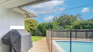 A backyard with a swimming pool, a covered grill, and a fenced area. - Riviera Beach Home w/ Pool - Walk to Beaches! (Singer Island)