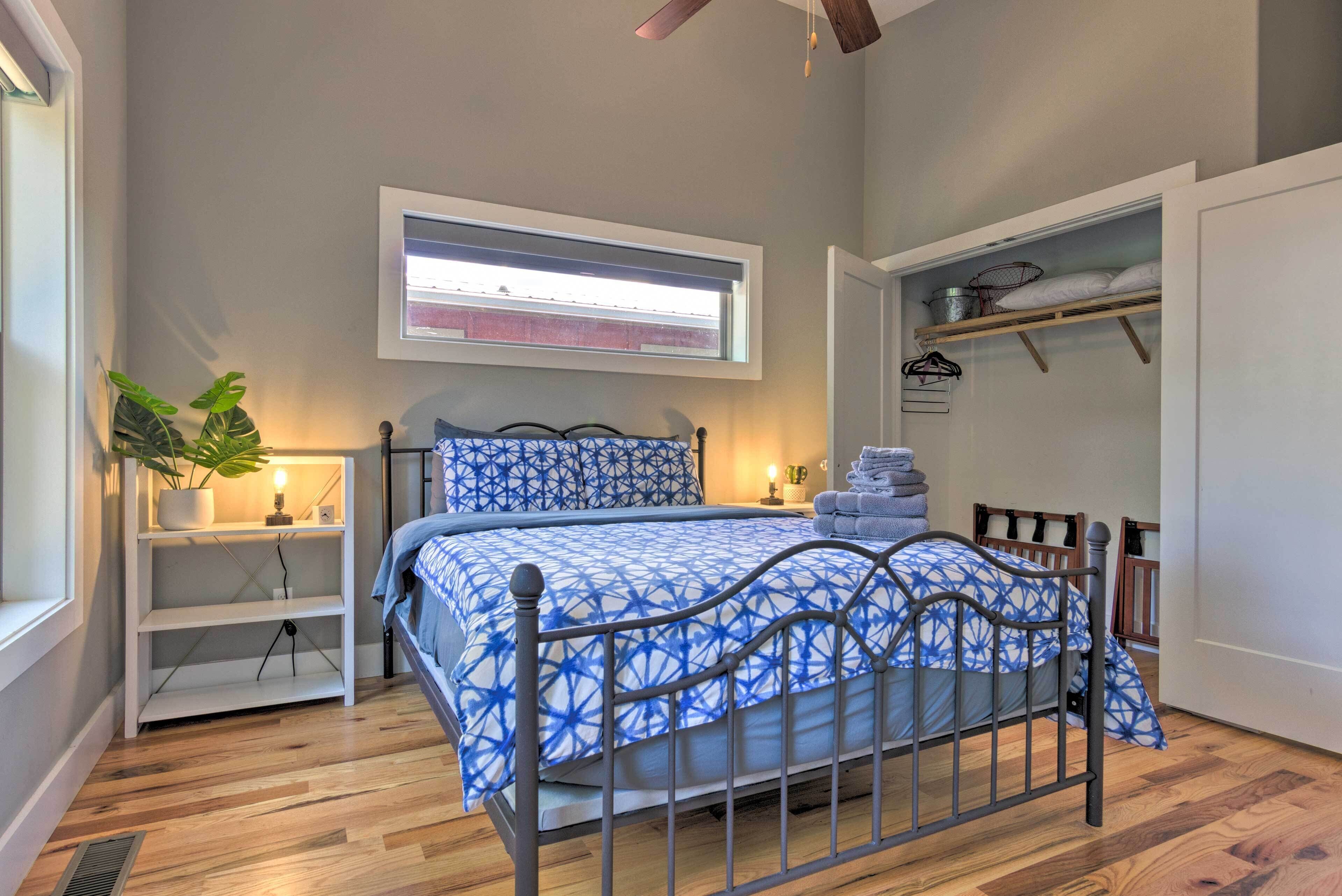 A bedroom with a bed, a nightstand, a potted plant, a window, and a closet.