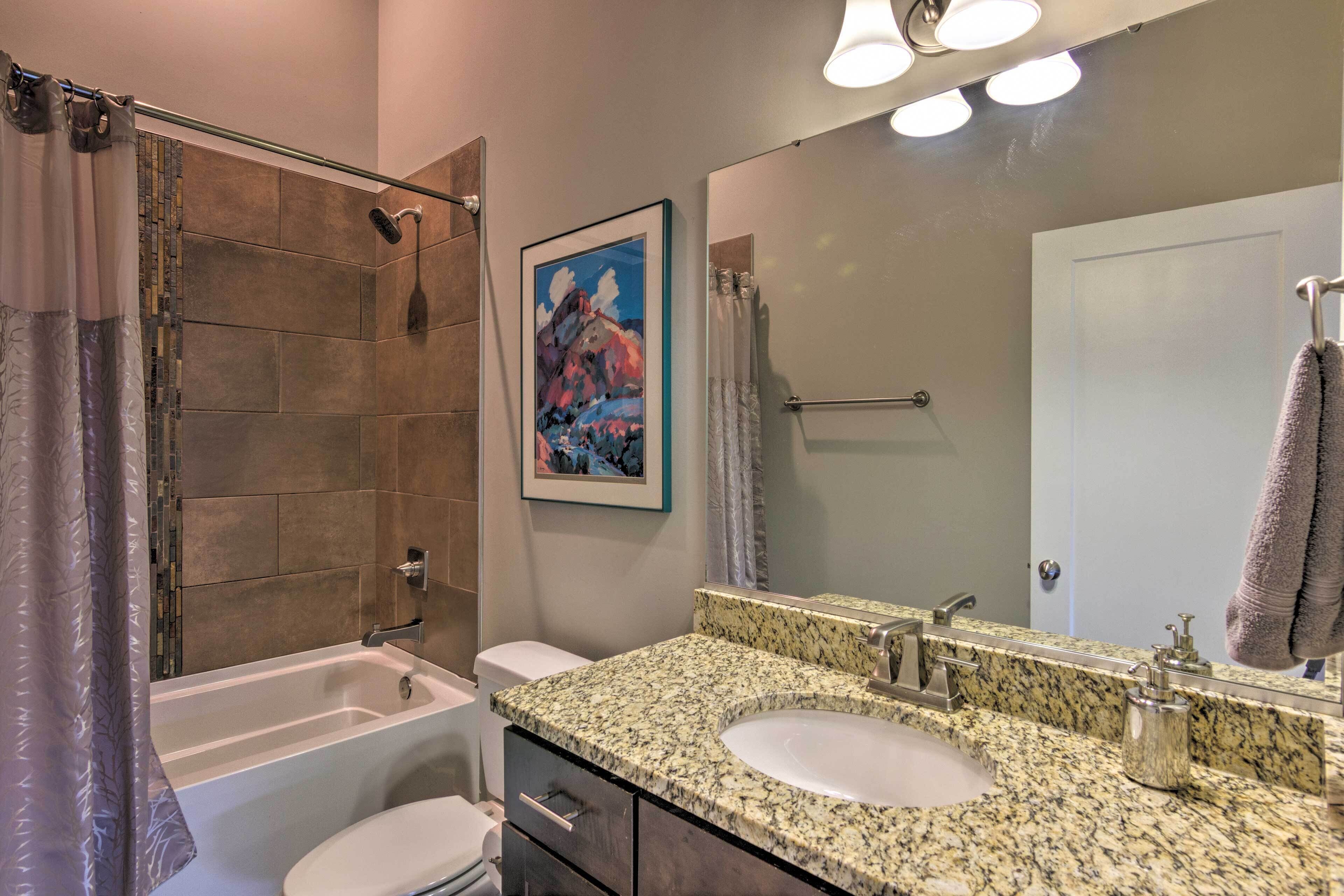 A bathroom with a bathtub, a sink, a toilet, and a shower area.
