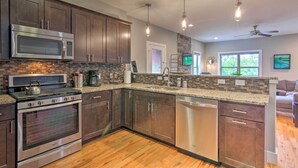 A modern kitchen with stainless steel appliances, dark wood cabinets, and a stone backsplash. - Modern Asheville Greenway Residence w/ 2 Decks! (Asheville)